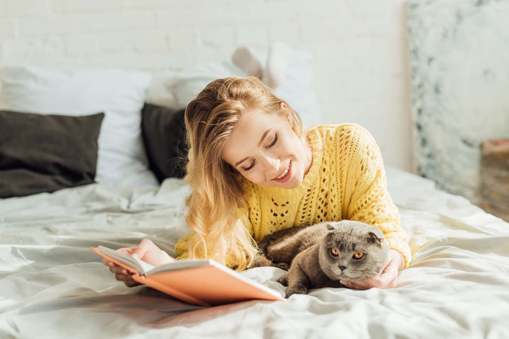 beautiful-smiling-young-woman-reading-book-while-l-WDL2SX9.jpg